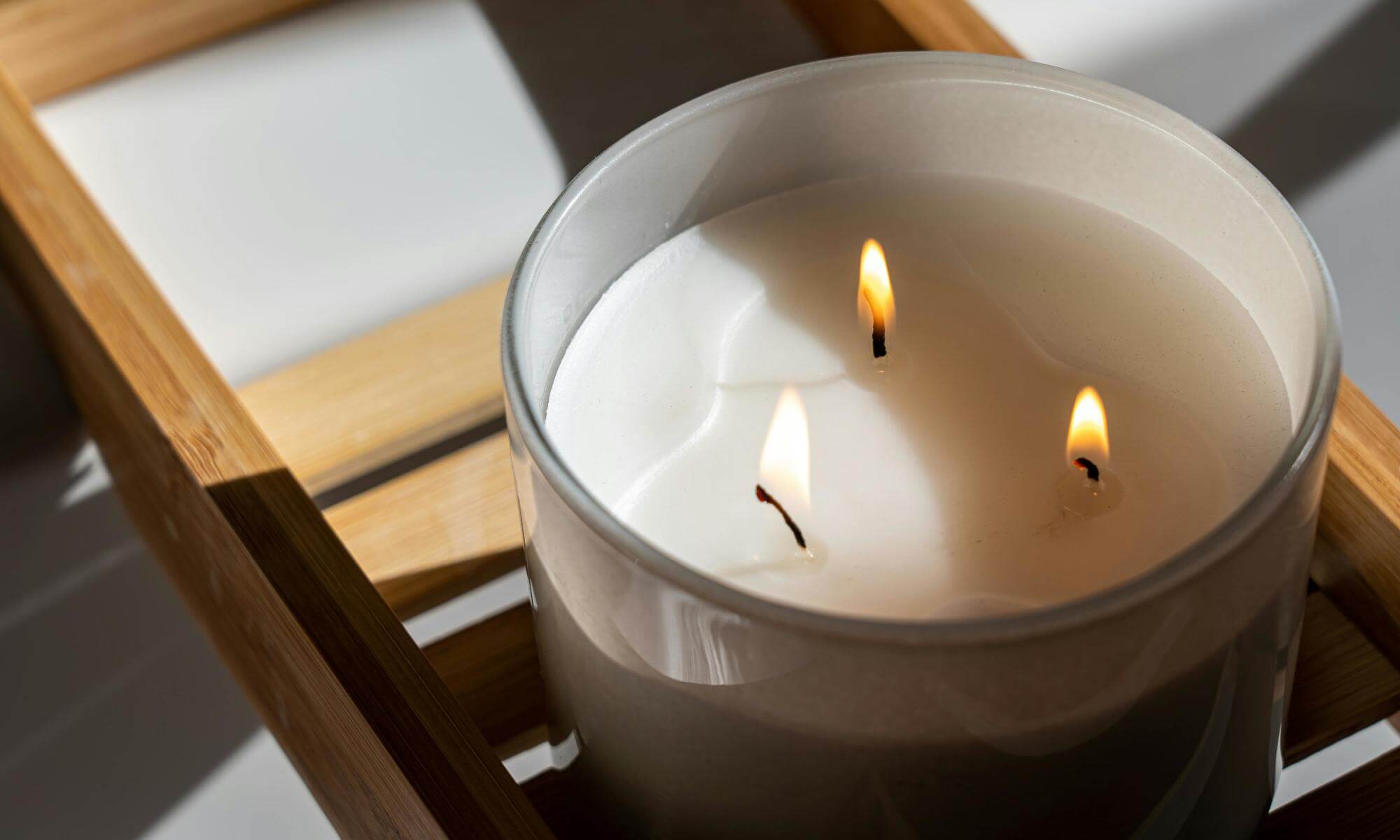 Świeca z trzema knotami na drewnianej podstawie.