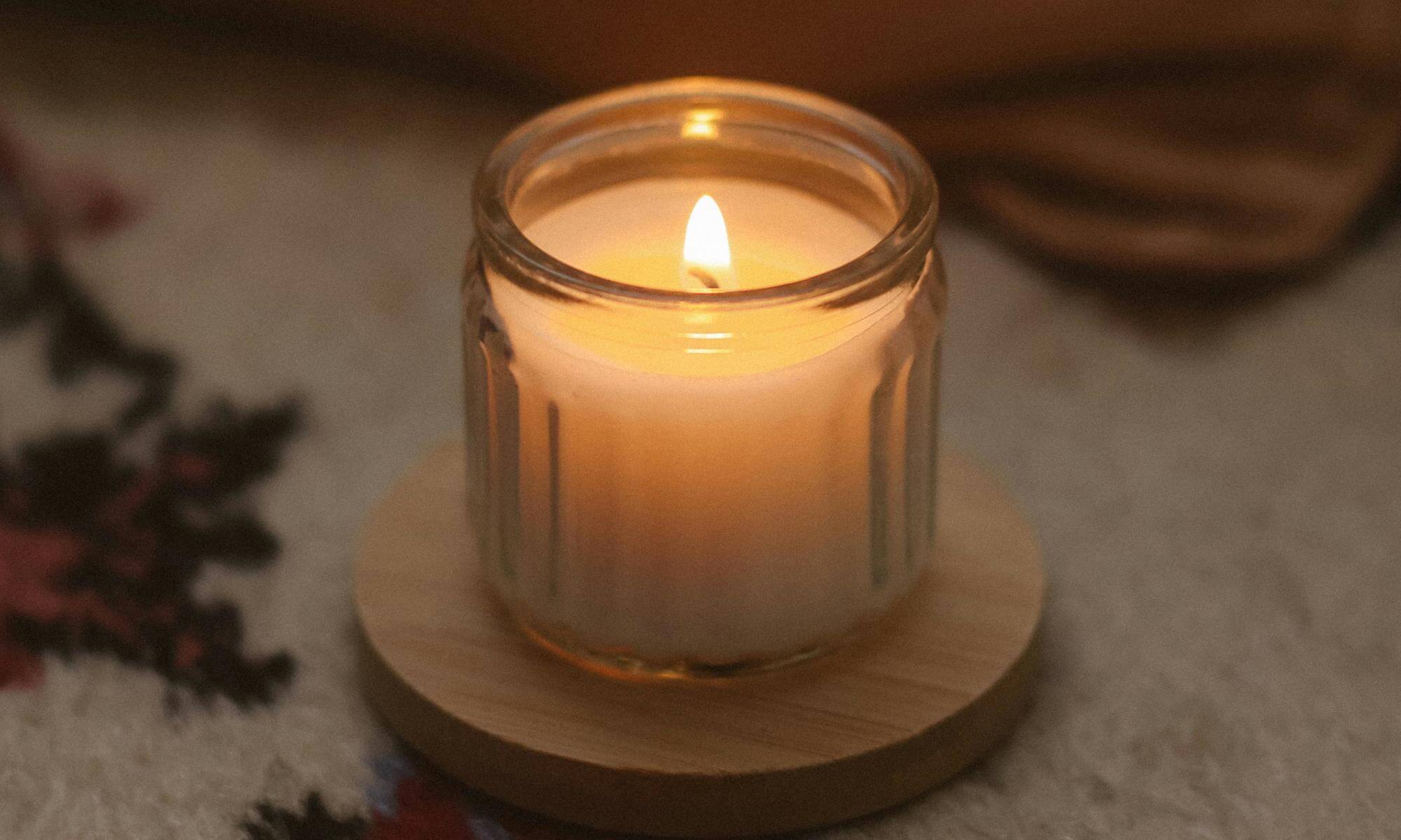 Świeca z jednym knotem w szklanym przeźroczystym pojemniku.