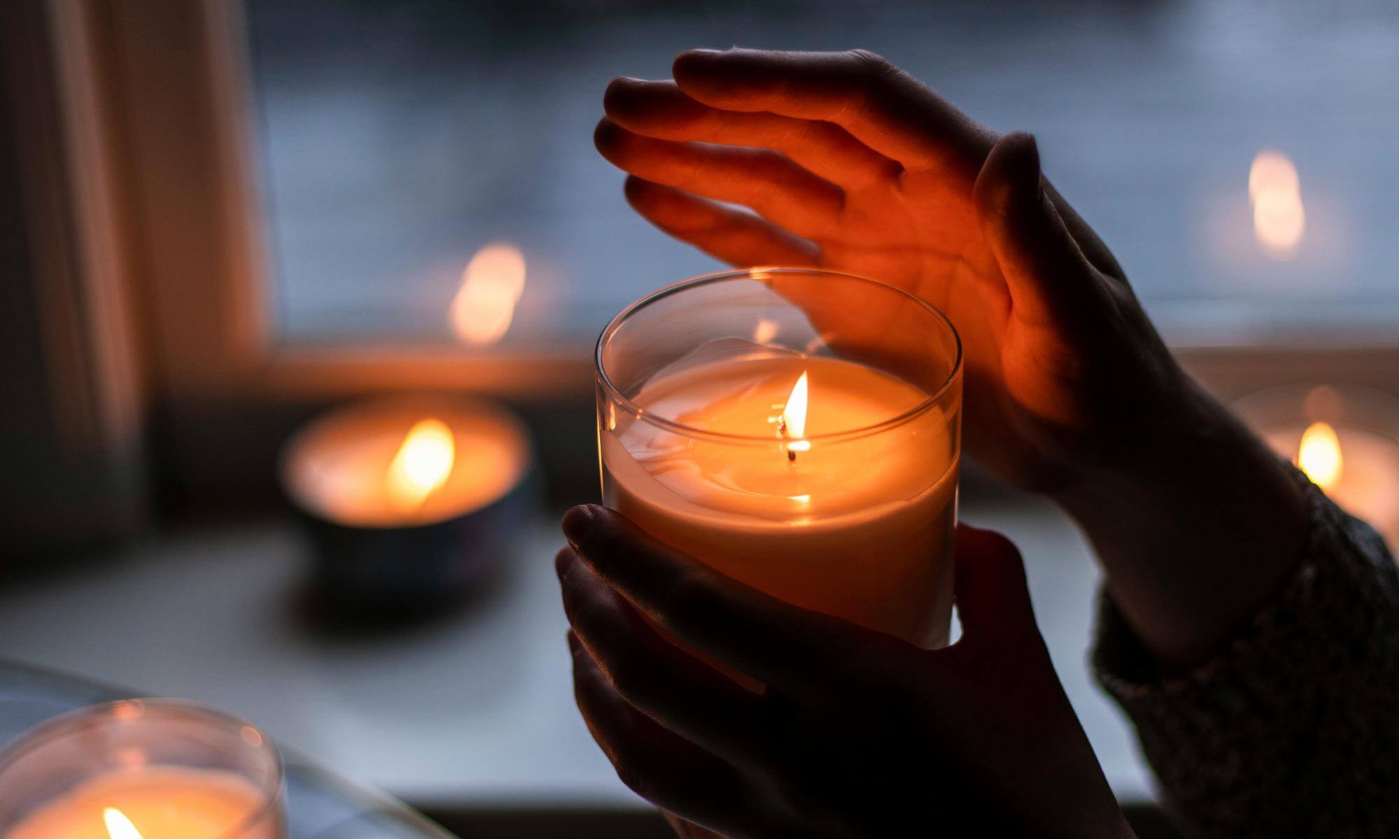 Świeca z jednym knotem trzymana w ręce.